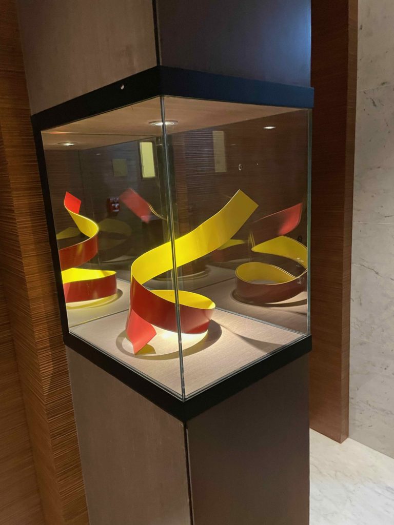 a glass case with a yellow and red spiral sculpture inside